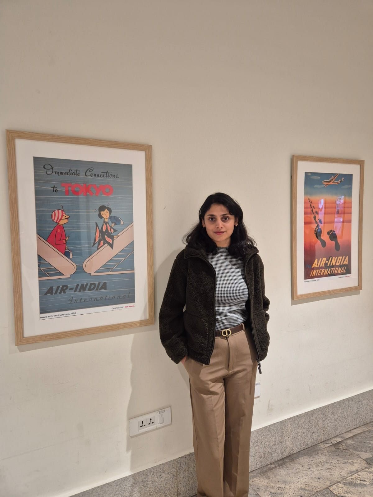 Website designer in Bengaluru beside framed vintage Air India travel posters at a design exhibition